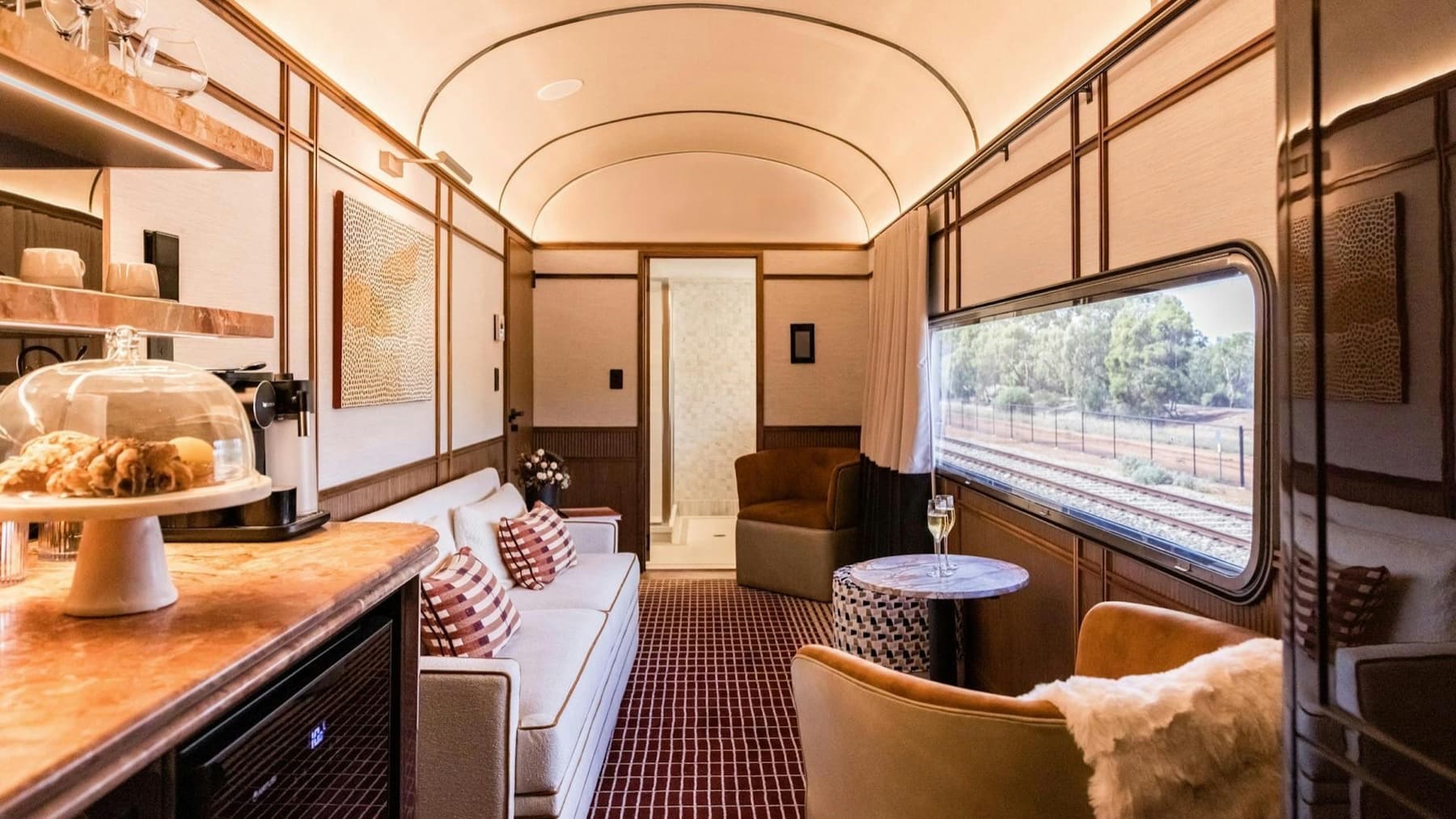 Australis Suite lounge aboard a Journey Beyond train, with seating, personal bar, and Australian scrubland visible through the window — Journey Beyond Finally Sells Australia by Suite