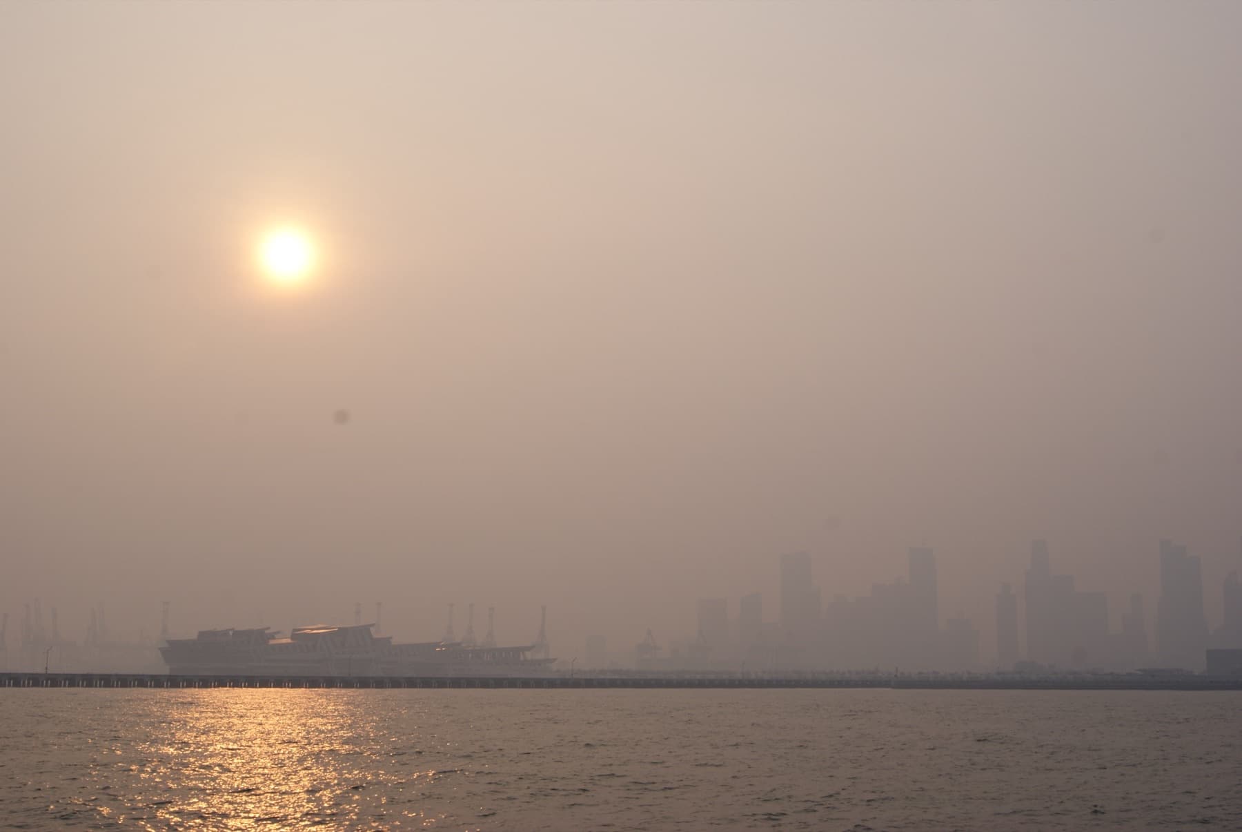 Singapore’s downtown skyline faded by thick haze, seen across the water at sunset