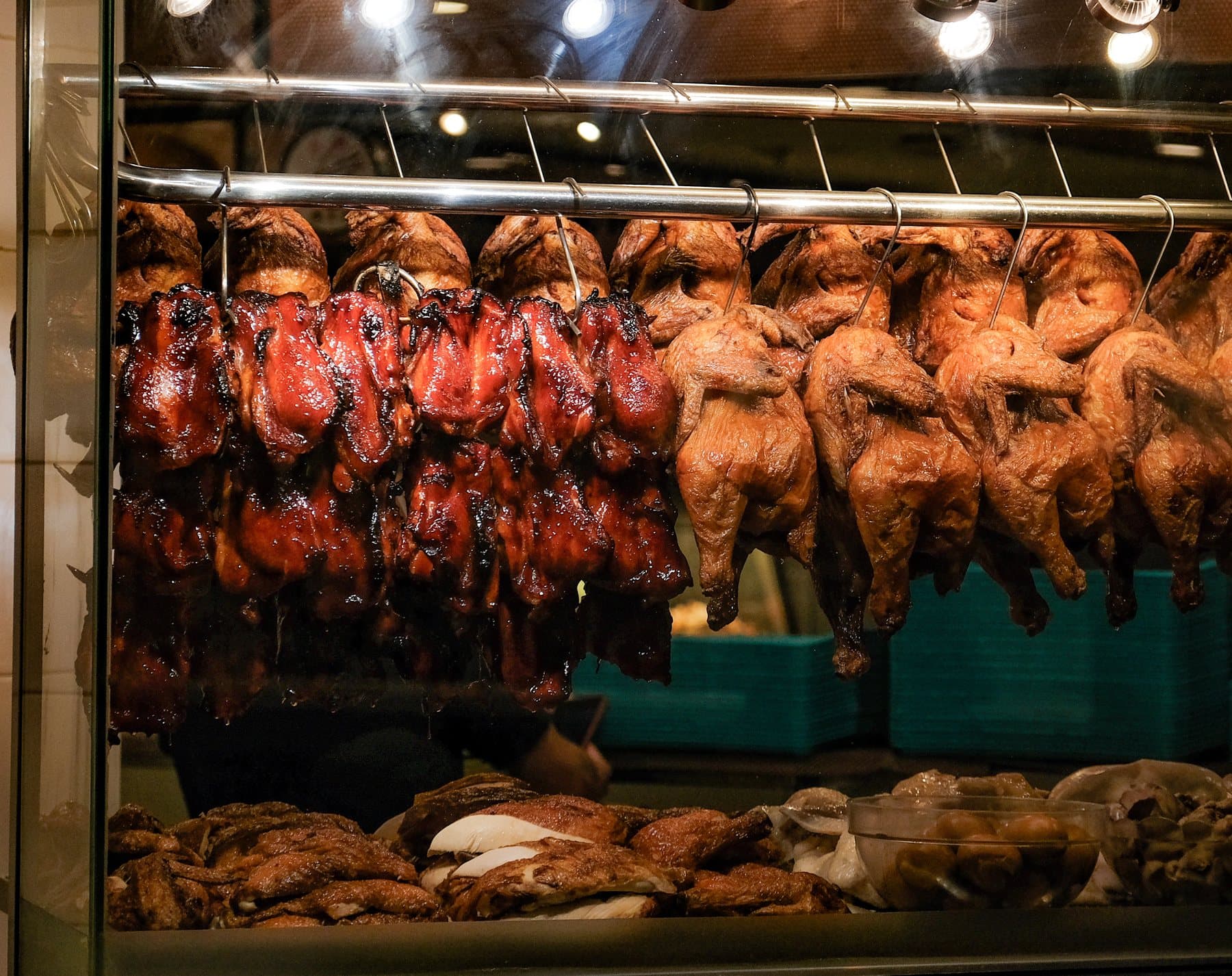 Roast and boiled chickens hanging in a glass stall window