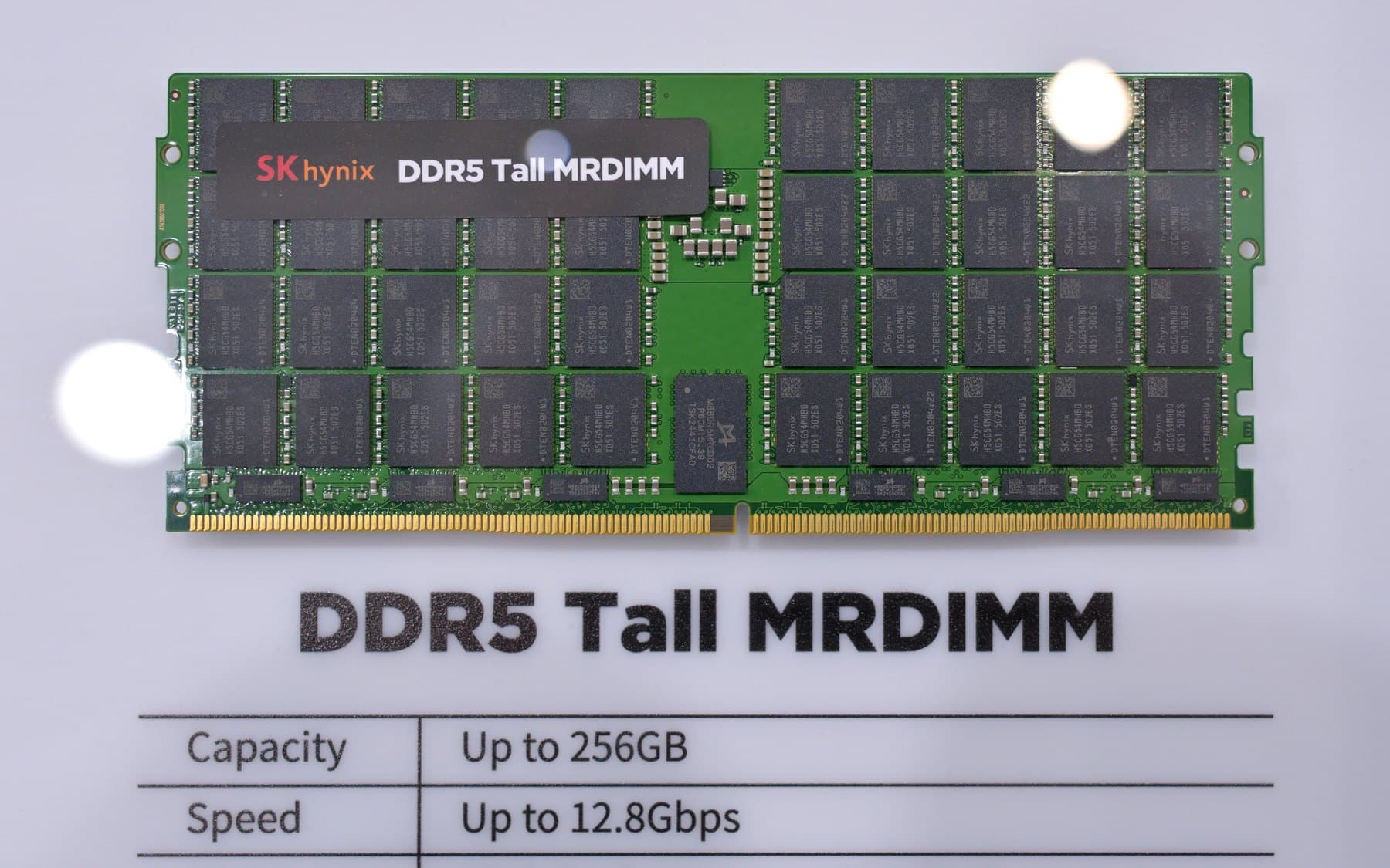 A green SK hynix DDR5 memory module covered in black chips, on a white display board
